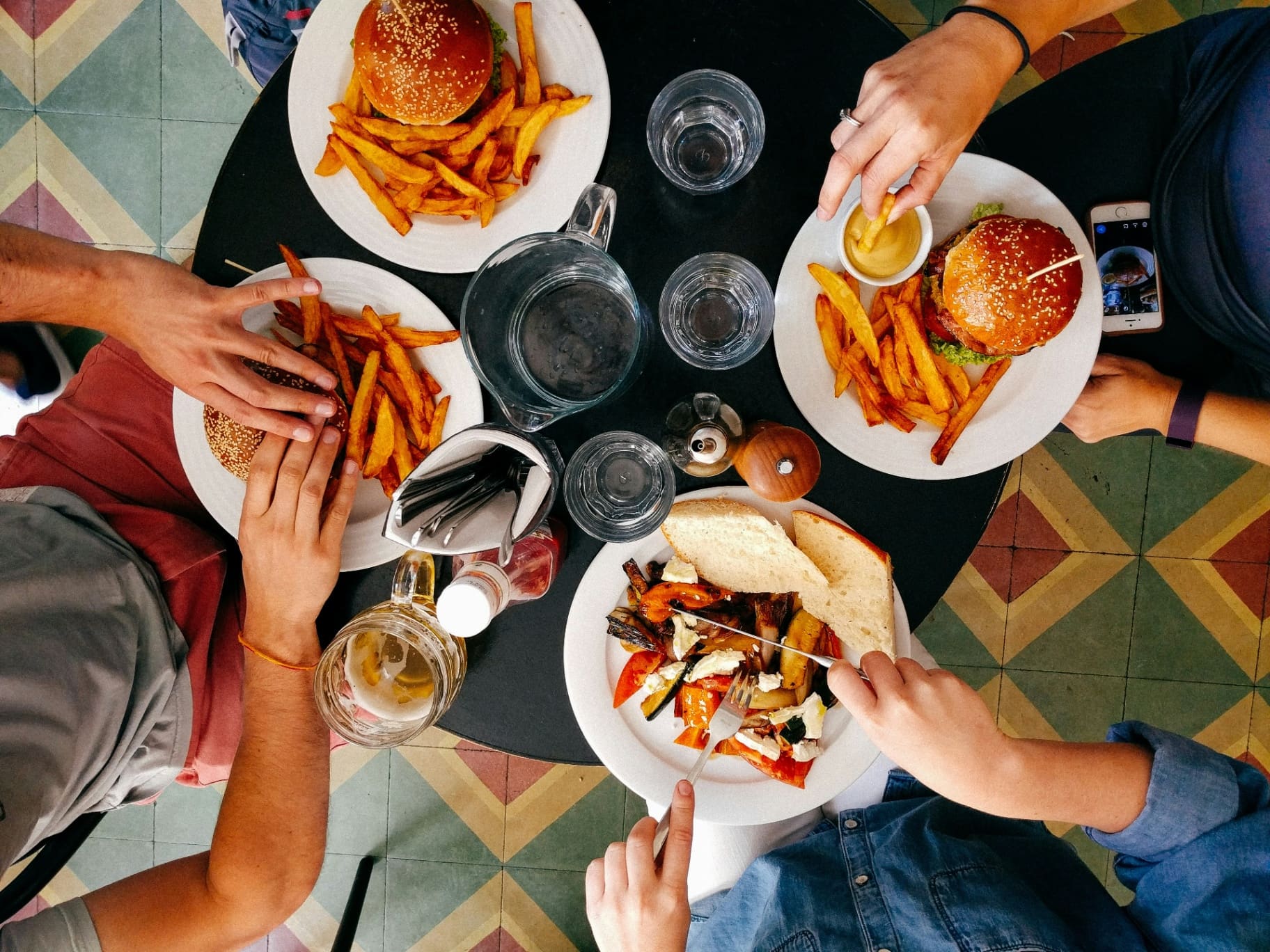 Overhead view of friends sharing burgers, fries and drinks at a restaurant — social media agency for hospitality brands