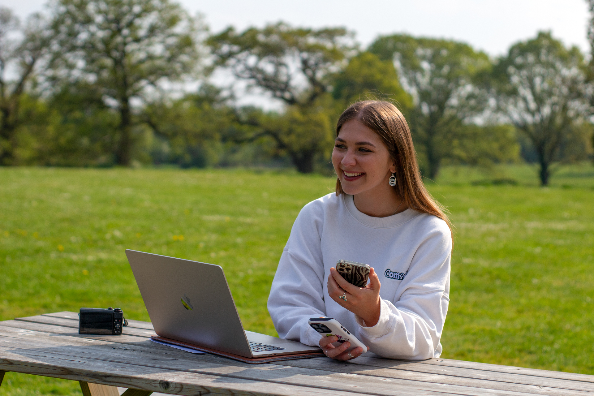 Compelite Pro UGC creator filming outdoors with a phone and laptop in a sunlit Bristol park